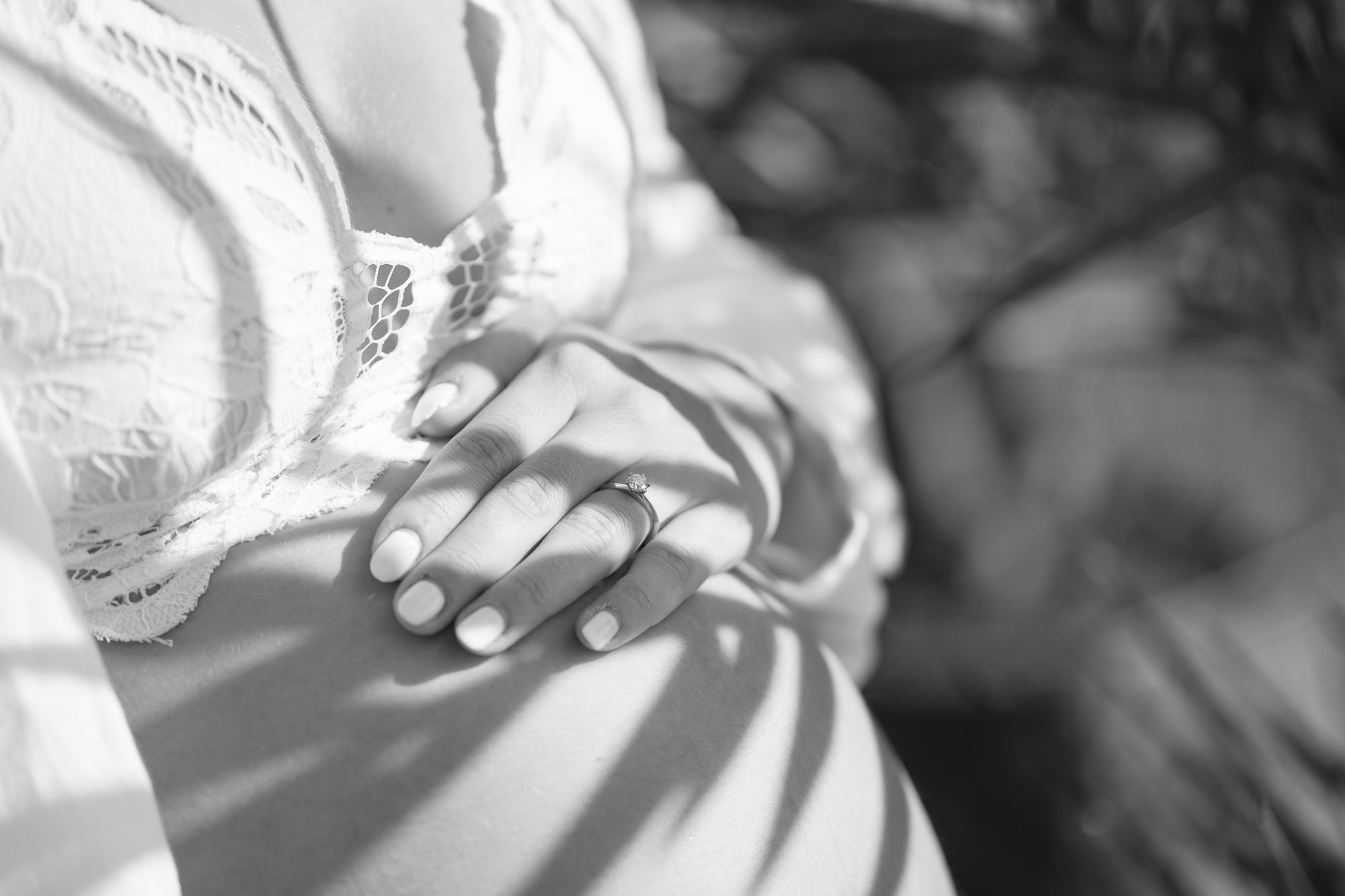 Babybauch mit Hand und Verlobungsring, schwarz-weiß