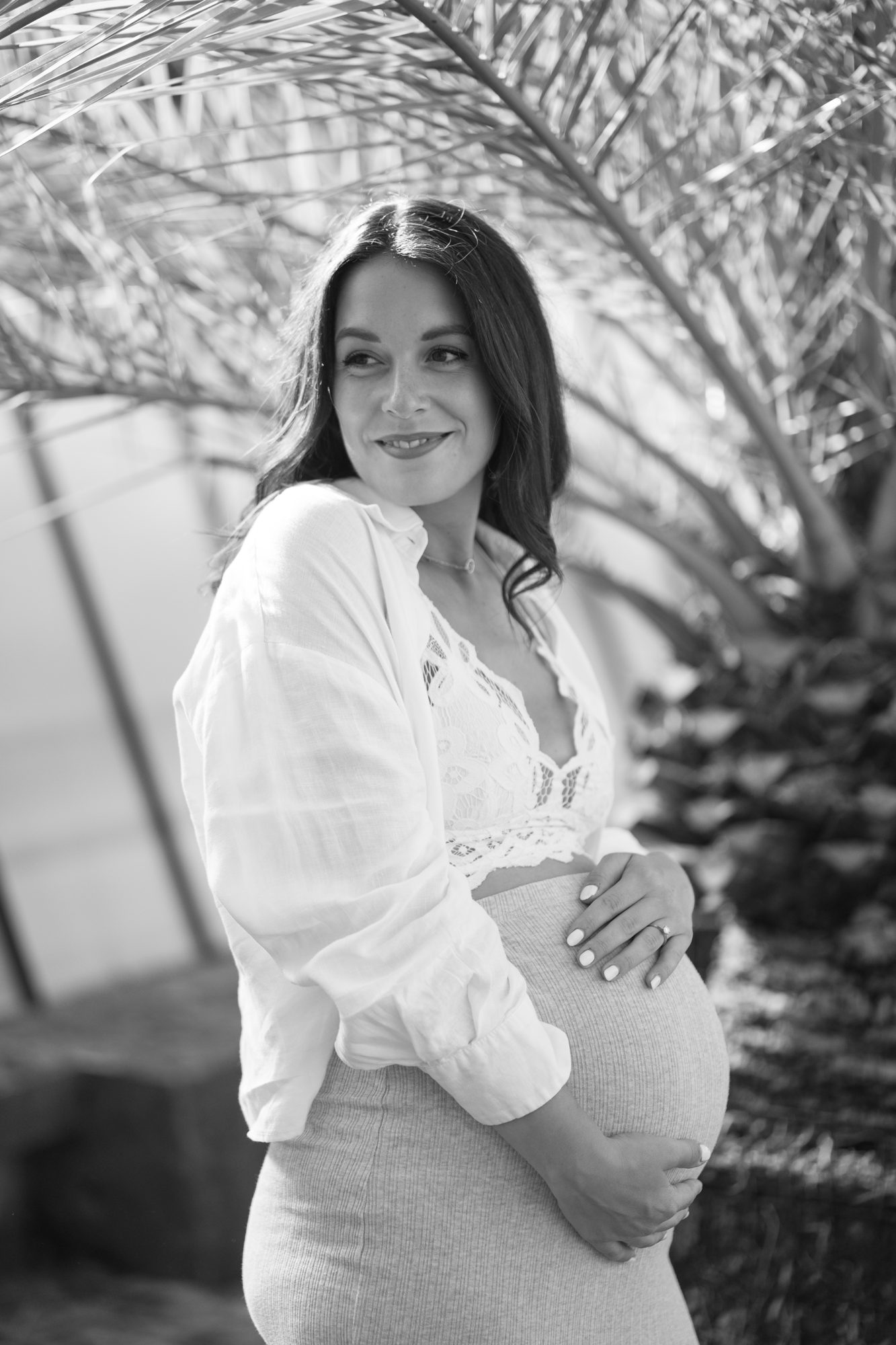 Schwangere im weißen Leinenhemd unter Palmen, schwarz-weiß — Babybauchfotografie München