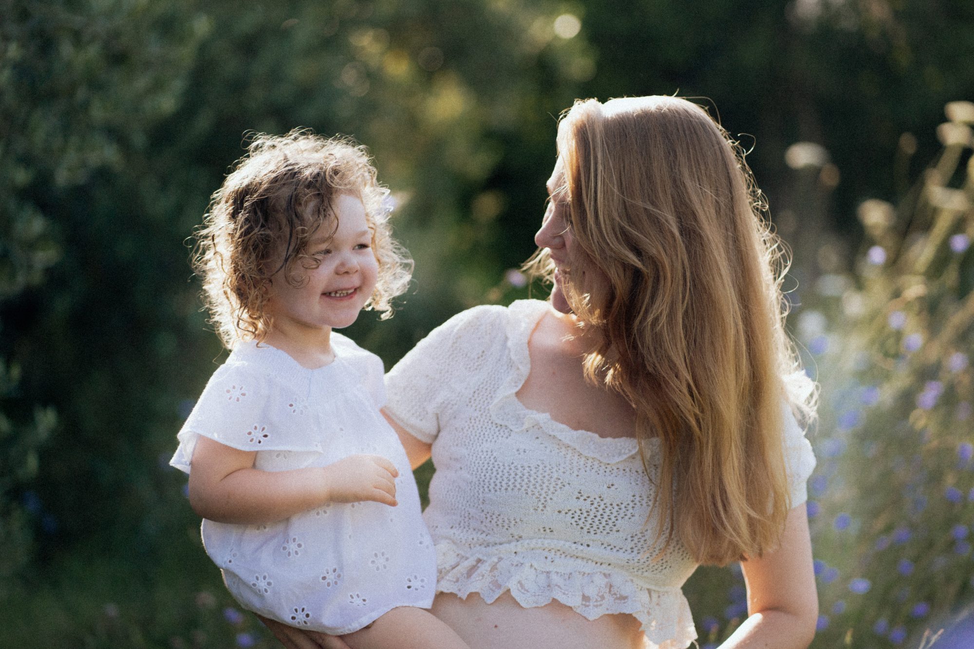 Mutter und Kind lachen sich an in der Blumenwiese — Familienfotografie