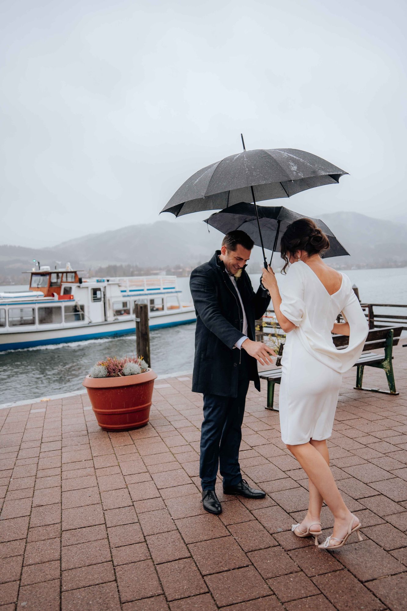 Regenhochzeit am Tegernsee — Brautpaar mit Regenschirmen am See