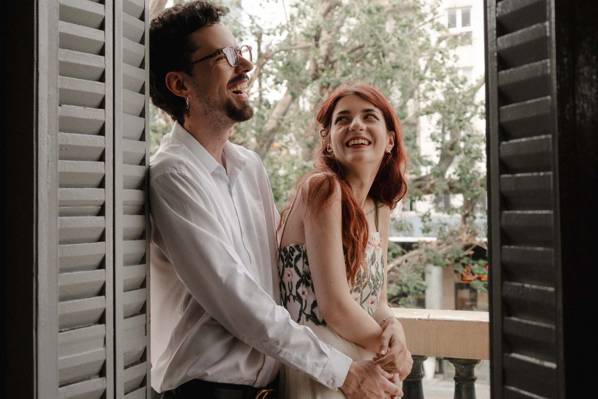 Paar lacht auf dem Balkon zwischen Fensterläden in Ho Chi Minh